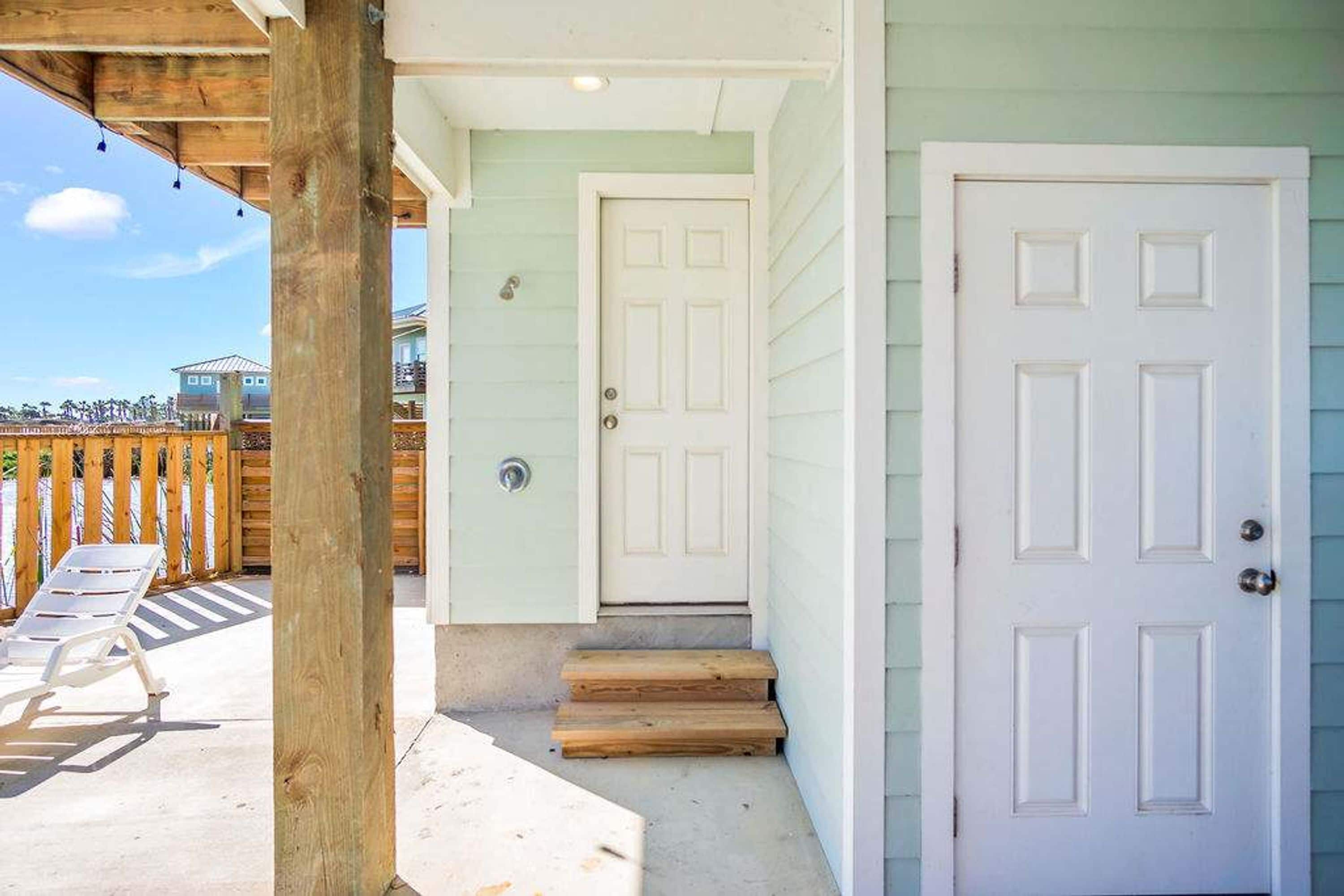 A wooden porch with a white door and a white door with a window.
