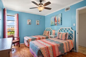 A room with two beds, a ceiling fan, a window with curtains, and artwork on the walls. - The Codfather- Family Friendly 2 Minute to Beach (Port Aransas)