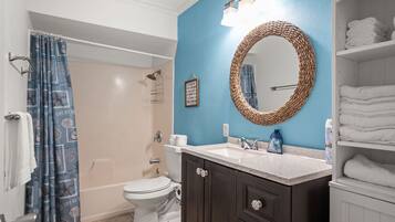 A bathroom with a white toilet, a sink with a mirror, and a shower area.