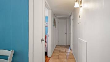 A hallway with white walls, a blue door, and a tiled floor.