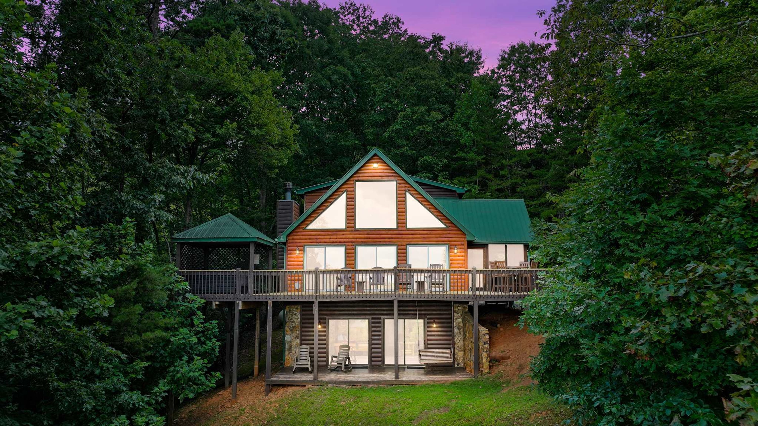A cabin with a balcony, surrounded by dense forest.