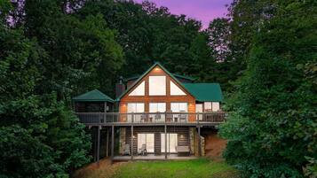 A cabin with a balcony, surrounded by dense forest.