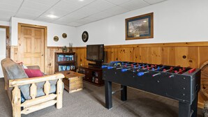 A cozy room with a wooden door, a sofa, a television, and a foosball table. - Mountain Views-hot Tub-games-pool Foosball (Morganton)