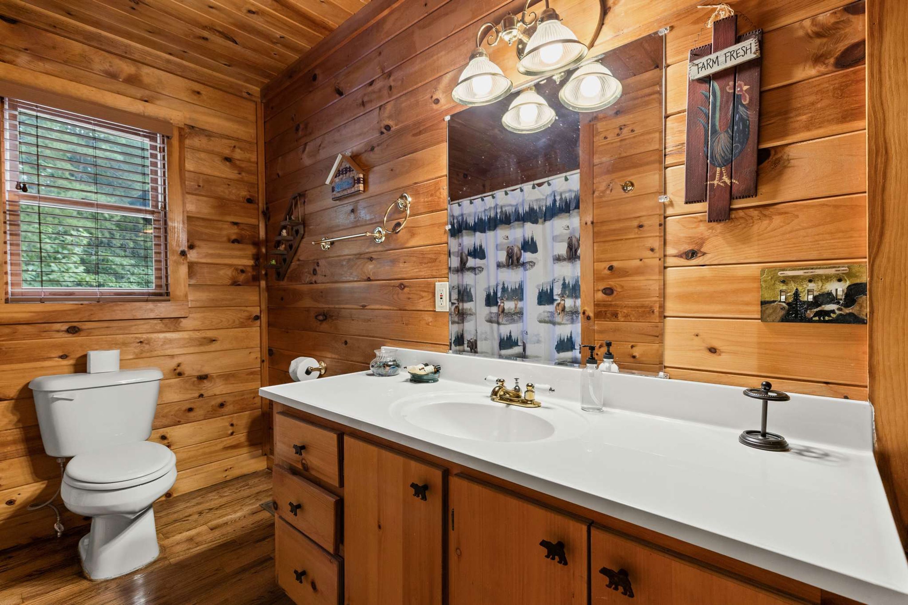 A wooden cabin bathroom with a toilet, sink, and vanity.