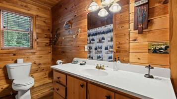 A wooden cabin bathroom with a toilet, sink, and vanity.