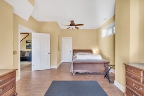 A bedroom with a bed, a ceiling fan, a dresser, and a door leading to another room. - Lakefront Dock Hot tub Firepit Dog Friendly (Mill Spring)