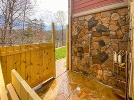 Un cerramiento de ducha de piedra con cubierta de madera y pared de piedra.