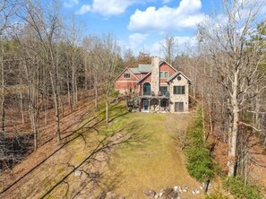 A two-story house with a stone exterior, a front porch, and a well-maintained lawn. - Lakefront Dock Hot tub Firepit Dog Friendly (Mill Spring)