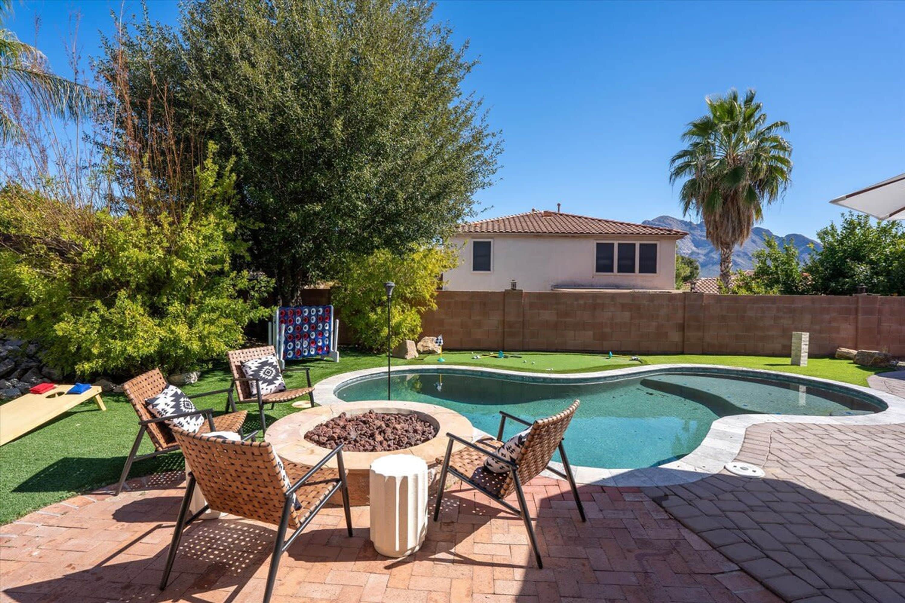 A backyard with a swimming pool, outdoor furniture, and a house in the background.