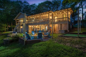 Ein zweistöckiges Holzhaus mit verdeckter Veranda, Sitzbereich im Freien und einem kleinen Putting-Green.