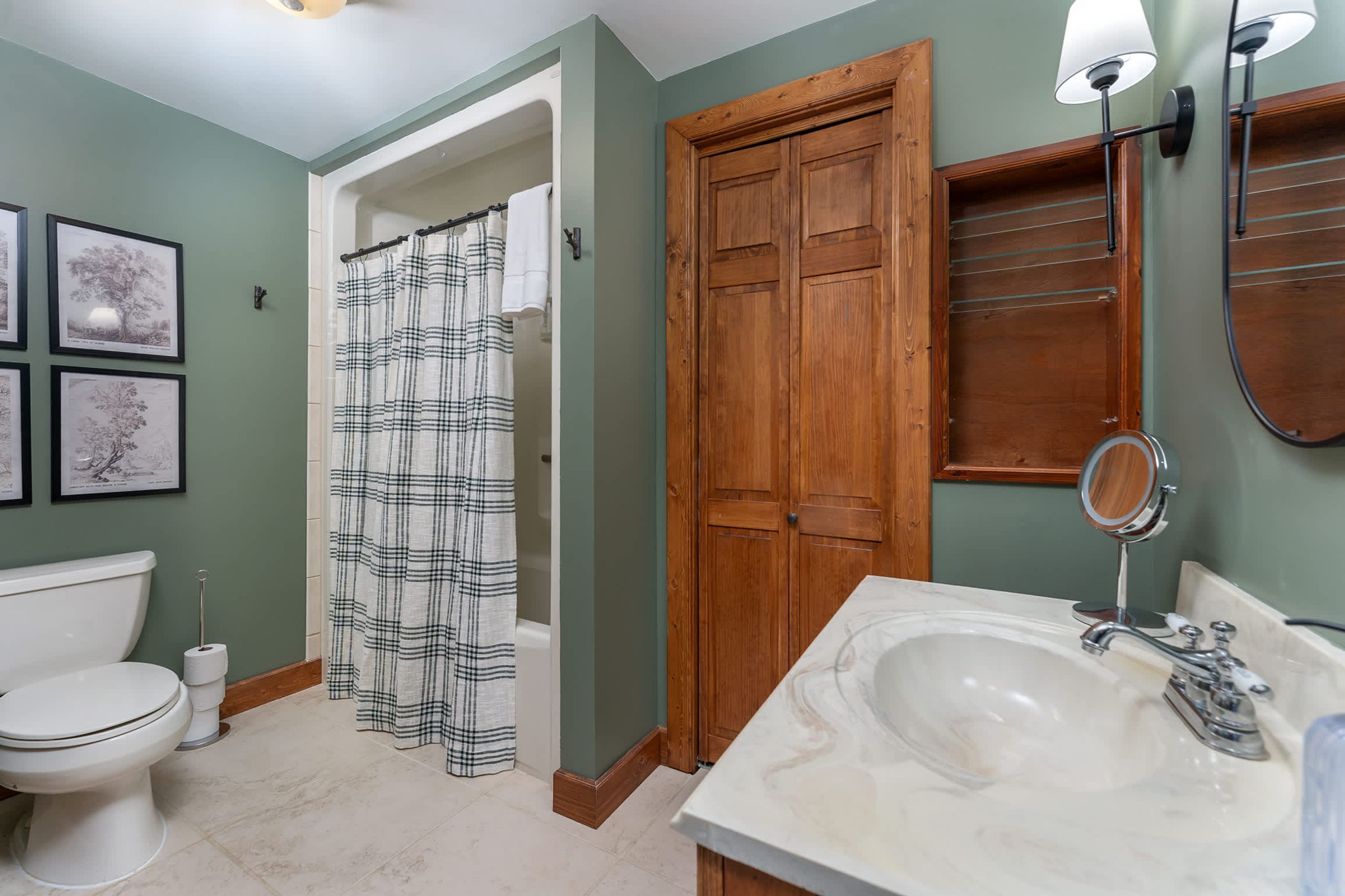 Une salle de bain avec des toilettes, un lavabo avec un miroir et un rideau de douche.