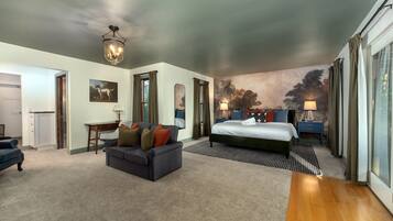 A hotel room with a bed, a sofa, a desk, and a large painting on the wall.