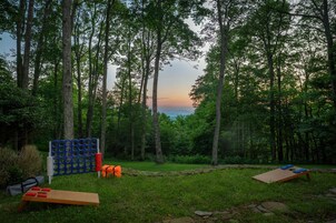 An outdoor setting with a wooden table, a blue and red structure, and a view of trees and sky.
