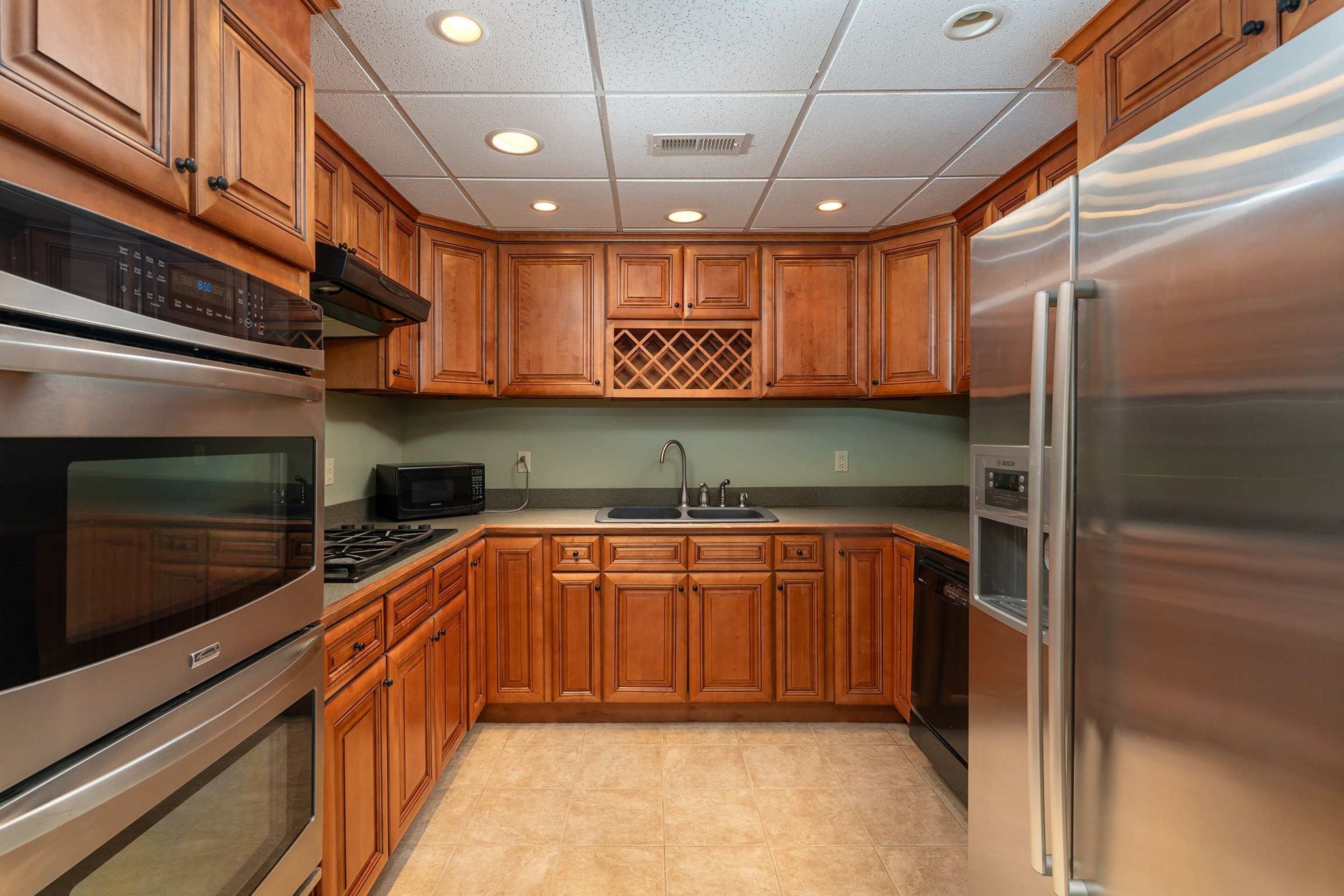 A kitchen with wooden cabinets, stainless steel appliances, a microwave, and a sink.