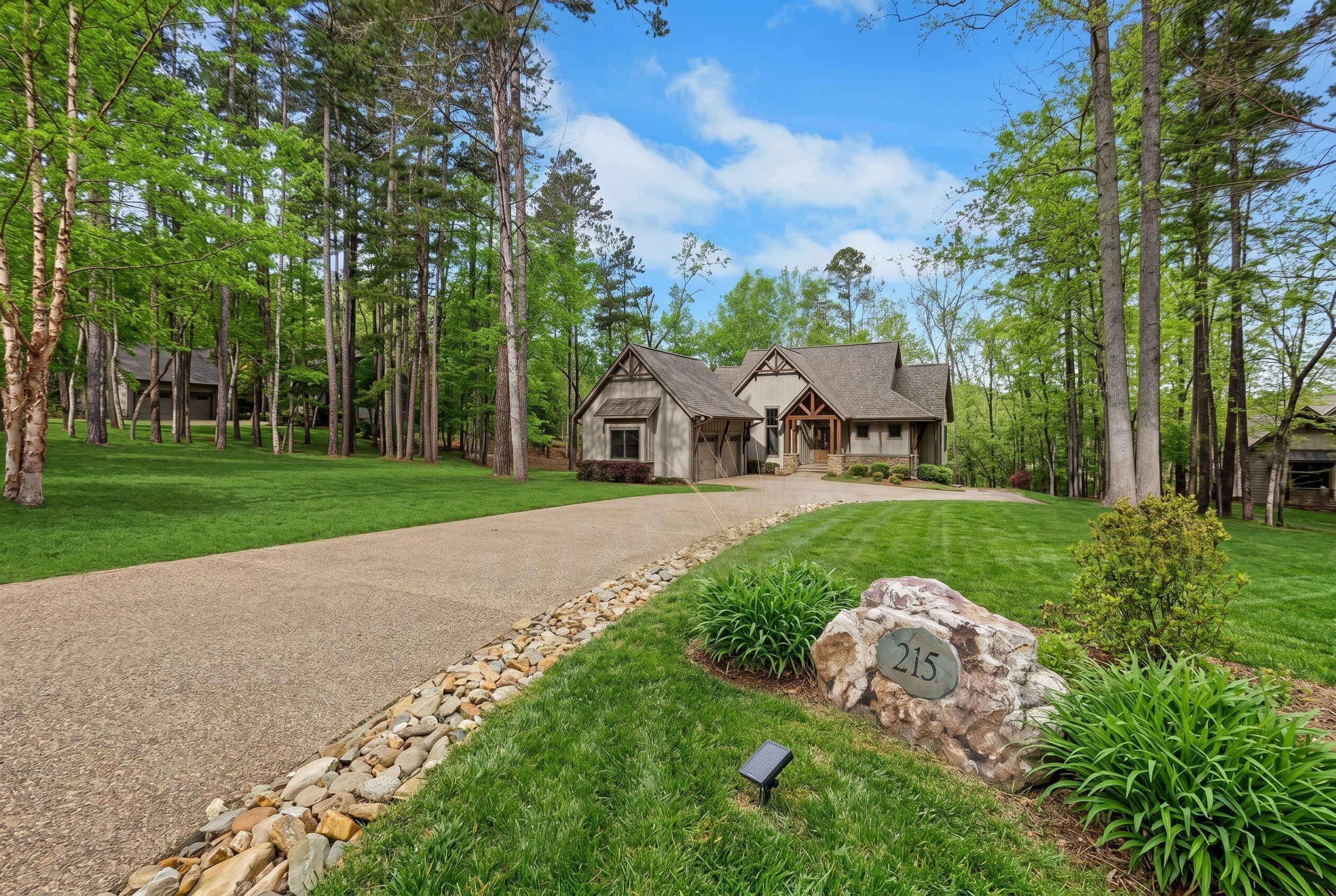 A two-story house with a stone pathway leading to the entrance, surrounded by a well-maintained lawn and tall trees.