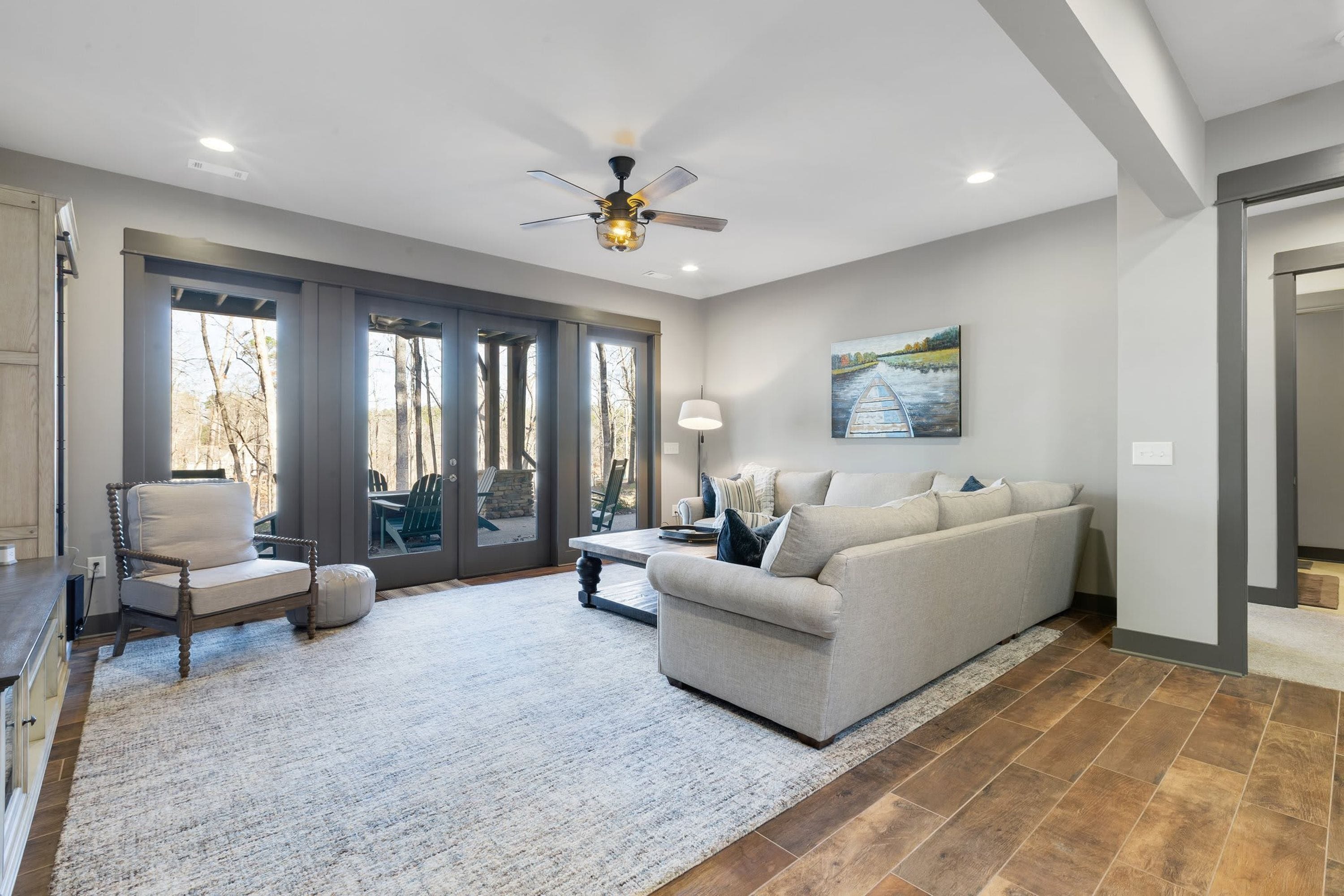 A spacious living room with a large sofa, a dining table, and a ceiling fan.
