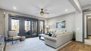 A spacious living room with a large sofa, a dining table, and a ceiling fan. - Lakefront Getaway Dock Fire Pit Kayak Games (Seneca)
