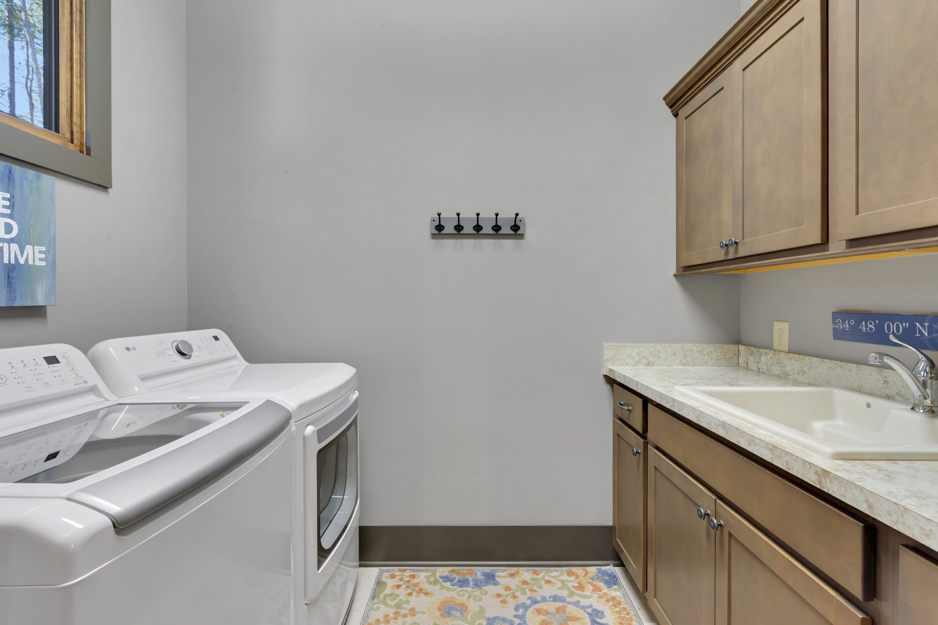 A laundry room with a washing machine, dryer, and a sink with a marble countertop.