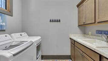 A laundry room with a washing machine, dryer, and a sink with a marble countertop.
