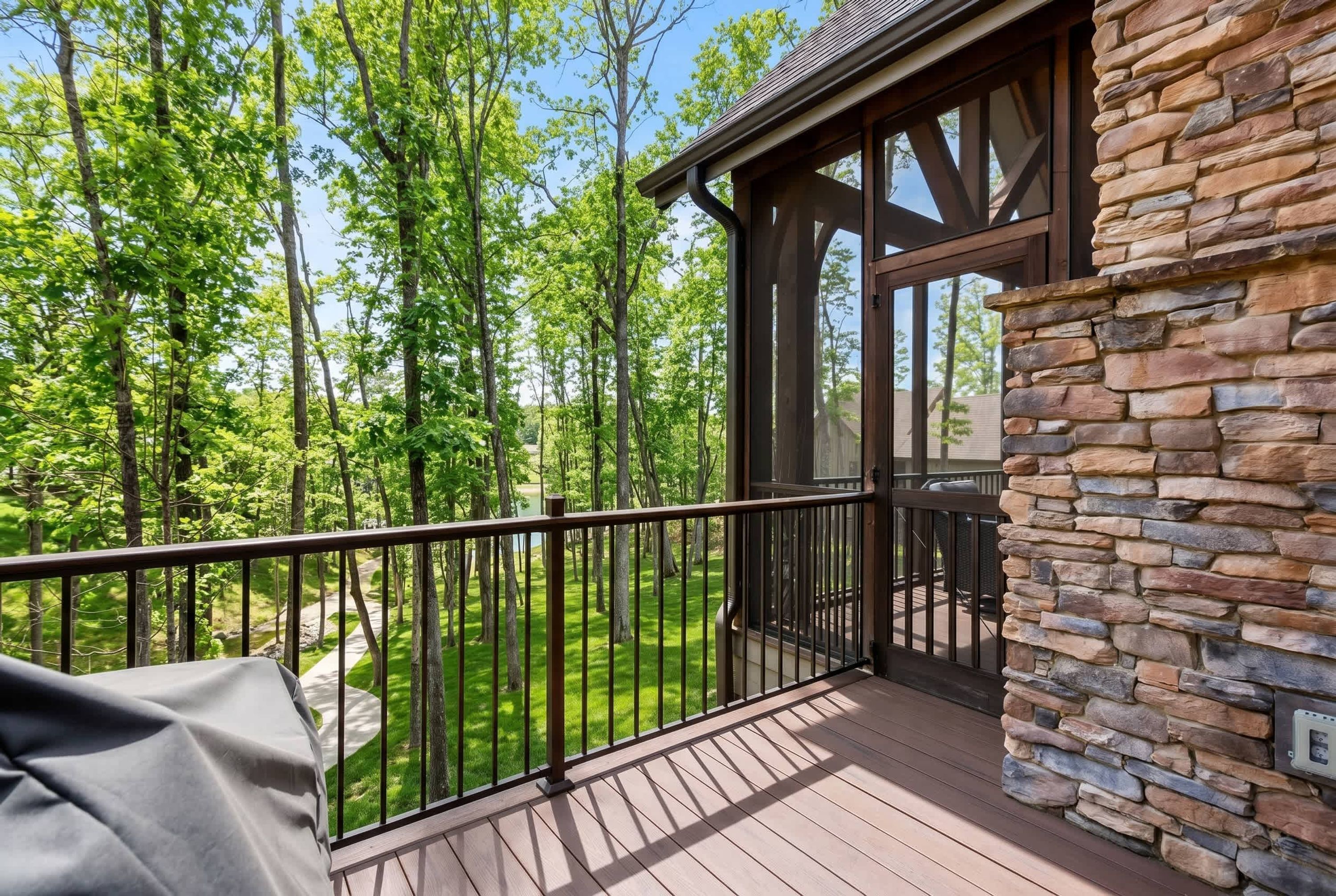 A wooden deck with a stone wall, overlooking a forested area.