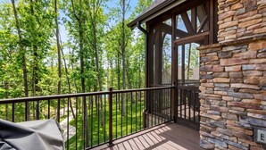 A wooden deck with a stone wall, overlooking a forested area. - Lakefront Getaway Dock Fire Pit Kayak Games (Seneca)