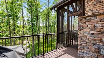 A wooden deck with a stone wall, overlooking a forested area.