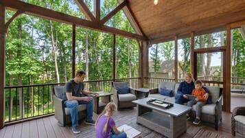 A covered outdoor seating area with wicker furniture and a wooden ceiling.