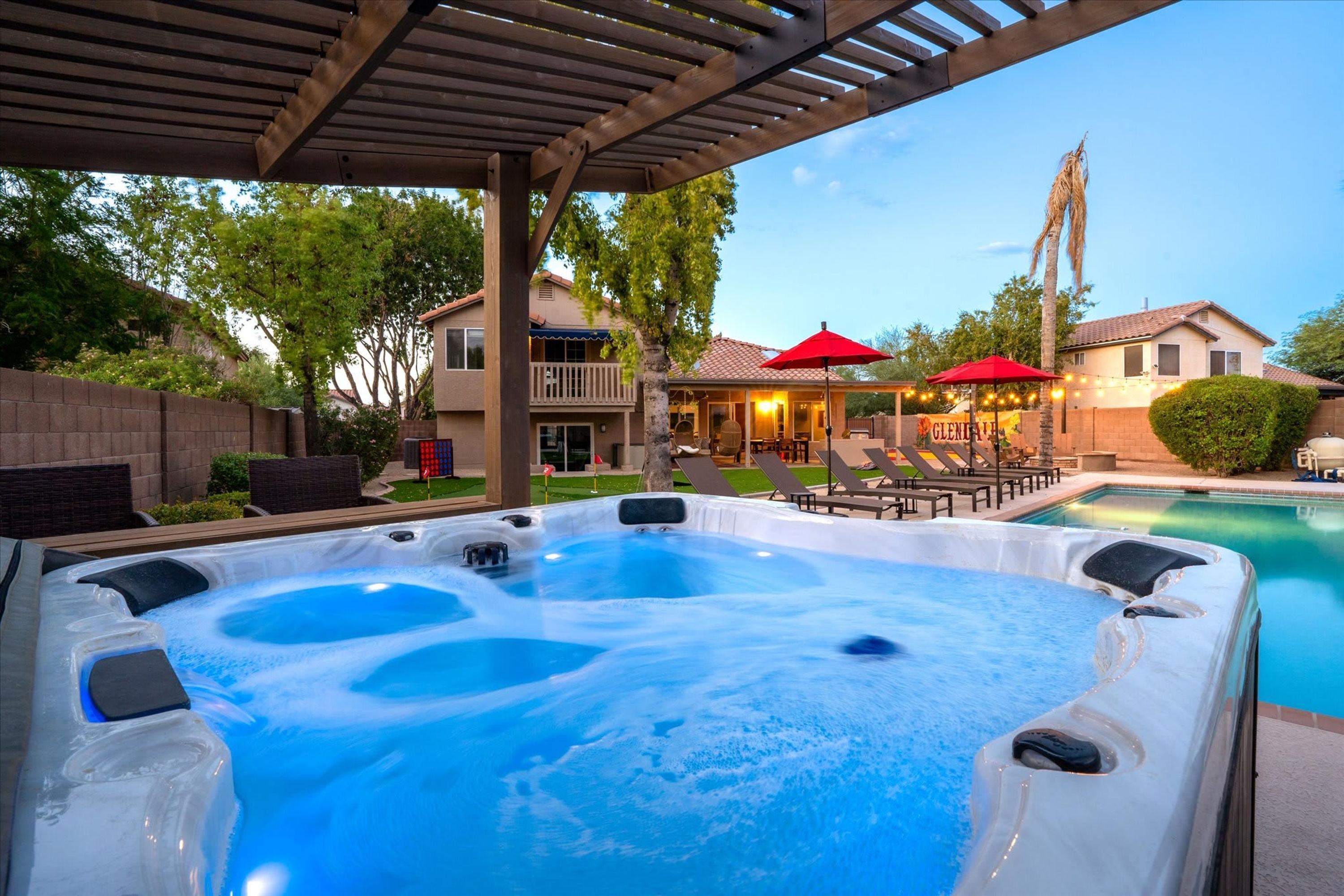 Un espace avec un jacuzzi, une piscine, des sièges extérieurs et un patio couvert.
