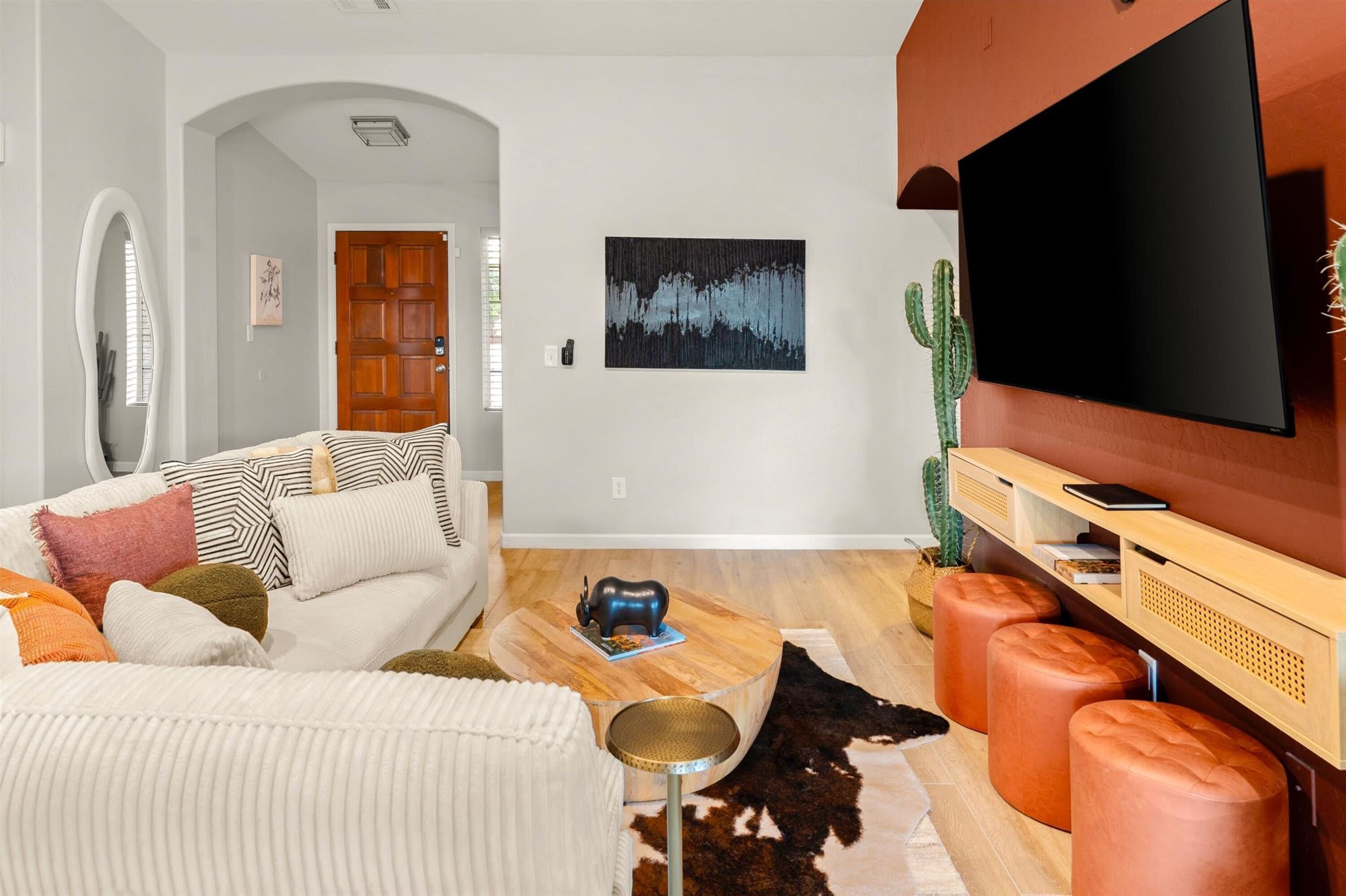 A living room with a sofa, a coffee table, a TV, and a cactus.