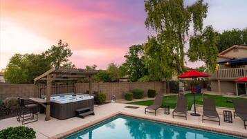 A backyard with a swimming pool, hot tub, and outdoor seating area.
