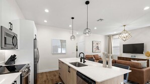 Une cuisine moderne dotée d’un îlot central, d’appareils électroménagers intégrés et d’un coin repas avec un canapé et un téléviseur.