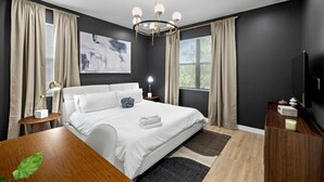 Une chambre à coucher moderne avec un grand lit, un lustre et un tableau au mur.