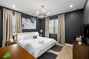 Ein modernes Schlafzimmer mit einem großen Bett, einer Kristallleuchter und einem Gemälde an der Wand.