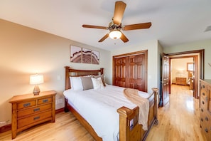 A bedroom with a wooden bed, a nightstand, a ceiling fan, and a door leading to another room. - Golden Ridge Lodge - Hot Tub - Games - Mtn Views (Helen)