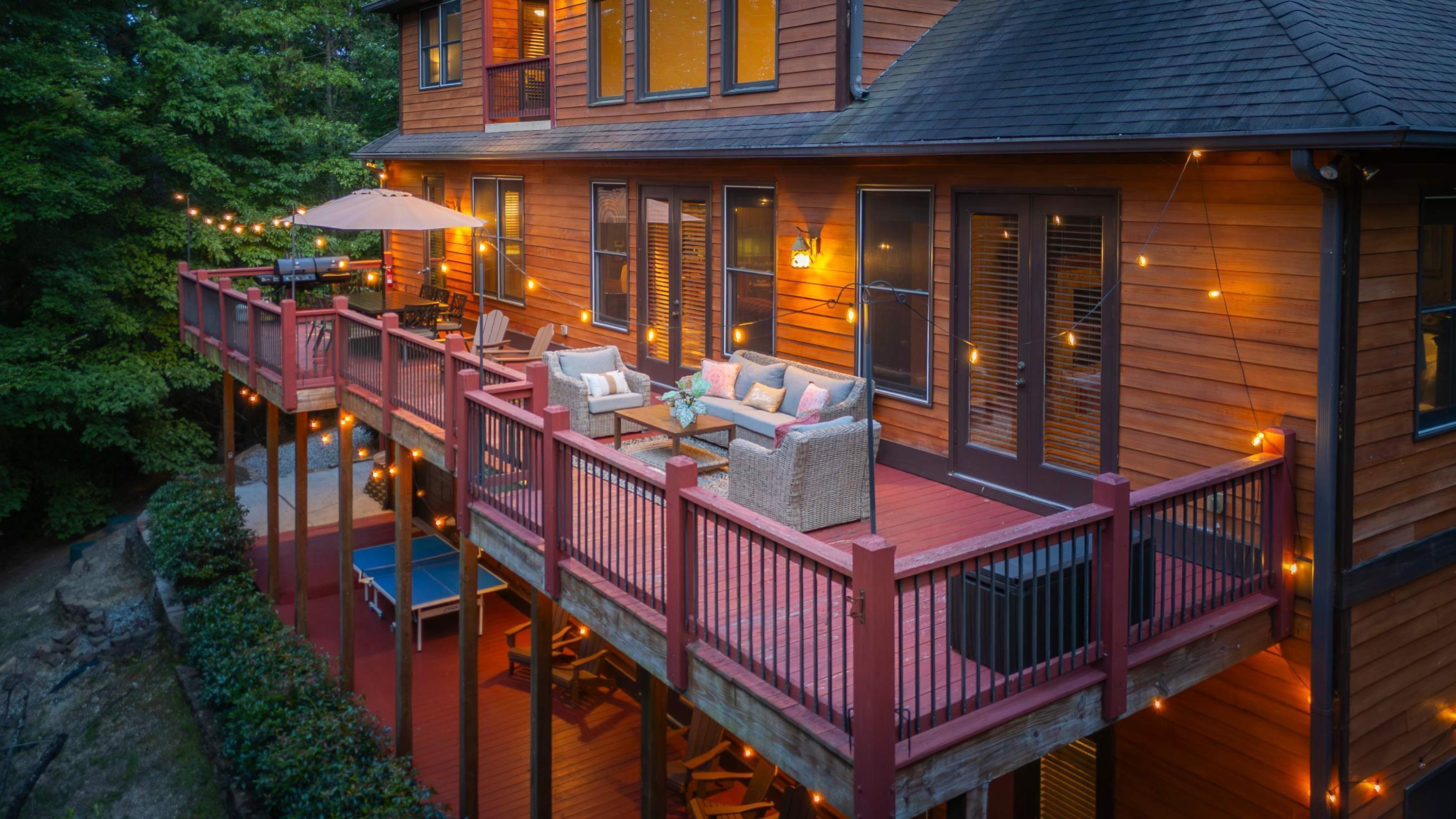 Ein Holzhaus mit einer Terrasse, Gartenmöbeln und Lichterketten.