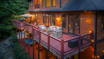 A wooden house with a deck, outdoor furniture, and string lights.