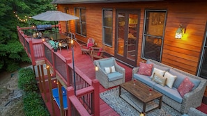 A wooden deck with outdoor furniture, a ping pong table, and string lights. - Golden Ridge Lodge - Hot Tub - Games - Mtn Views (Helen)