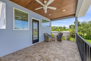 A covered outdoor area with a ceiling fan, two wicker chairs with cushions, and a view of greenery. - Sleeps 8 Private Pool Dog Friendly Balcony (Sarasota)
