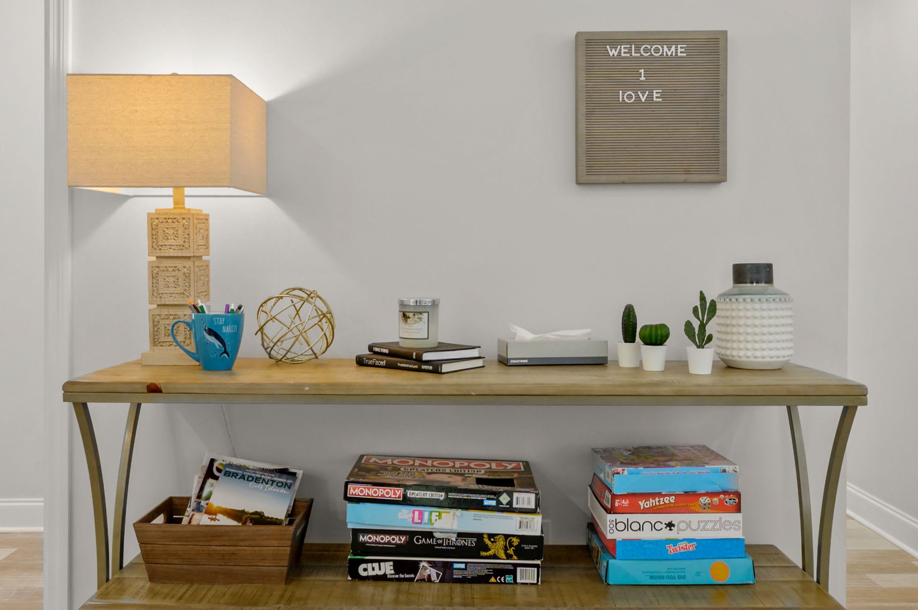 Un bureau en bois avec une lampe, des livres, une boîte de mouchoirs et de petites plantes.