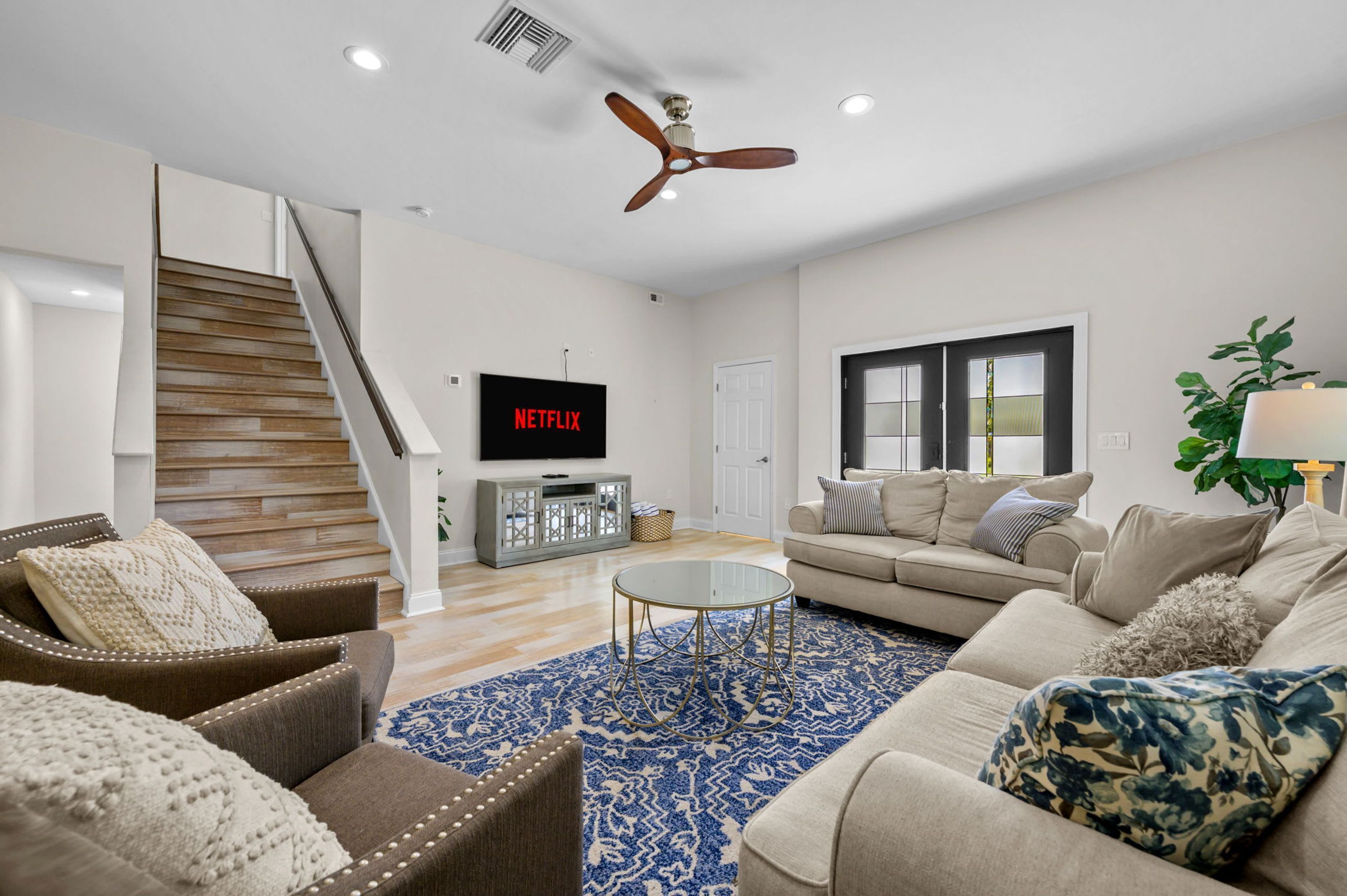 A living room with a staircase, a flat-screen TV, a sofa, and a coffee table.