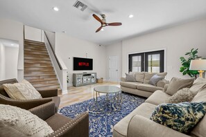 A living room with a staircase, a flat-screen TV, a sofa, and a coffee table. - Sleeps 8 Private Pool Dog Friendly Balcony (Sarasota)