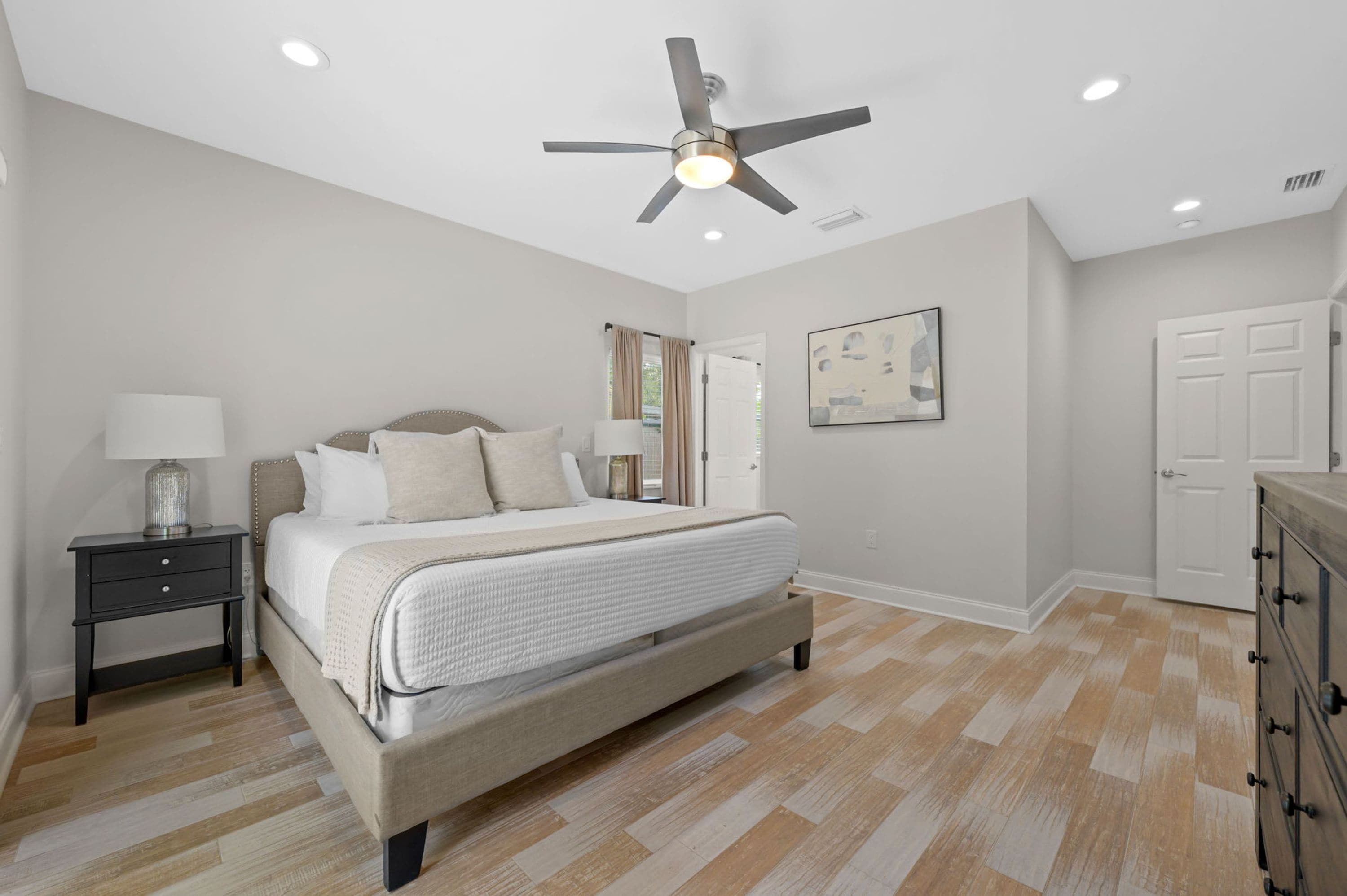 A bedroom with a bed, nightstands, a ceiling fan, and a dresser.