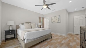 Ein Schlafzimmer mit einem Bett, Nachttischen, einem Deckenventilator und einer Kommode.