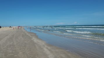 A beach with a sandy shore and calm waves.
