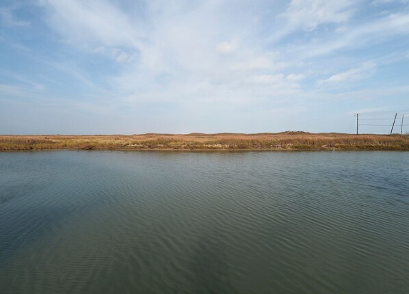 A calm body of water with a flat horizon and a clear sky.