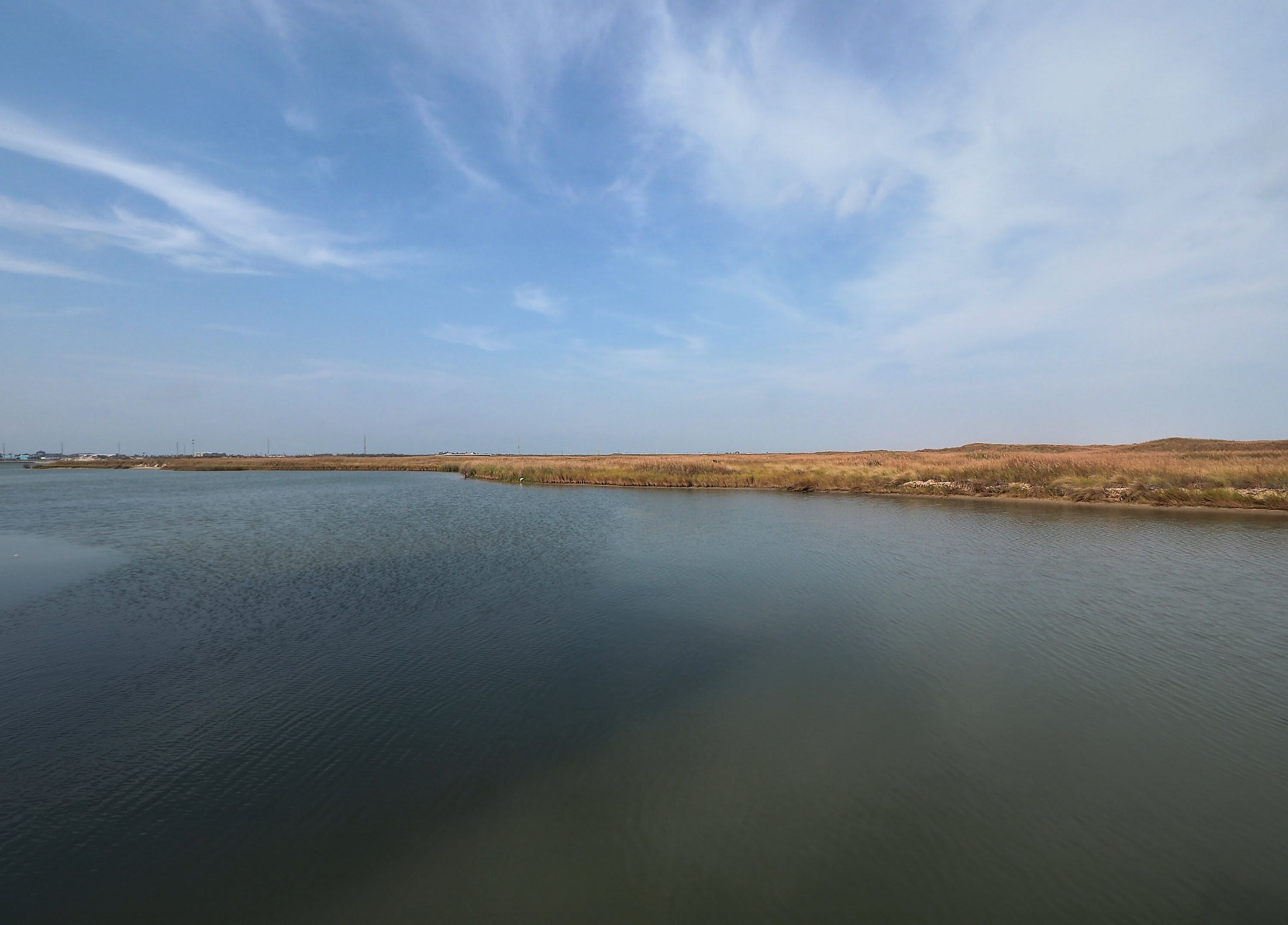 A calm body of water with a clear sky and distant land.