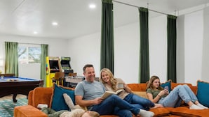A family in a living room with a pool table, a foosball table, and a sofa. - Fun-filled Oasis Pool Pickleball Games Galore (Scottsdale)