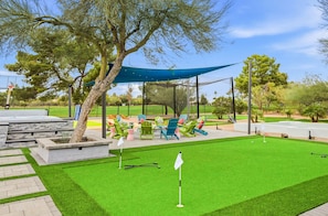 Ein gepflegter Golfplatz mit Putting-Grün, Abschlagbereich und einer Sitzgelegenheit mit Stühlen.