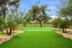 Ein Golfplatz mit gepflegtem Grün, einem Zaun und Bäumen.
