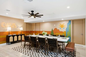 Ein Konferenzraum mit einem für eine Besprechung gedeckten Tisch, einem Deckenventilator und einer Wand mit dem Schriftzug 'OASIS'.